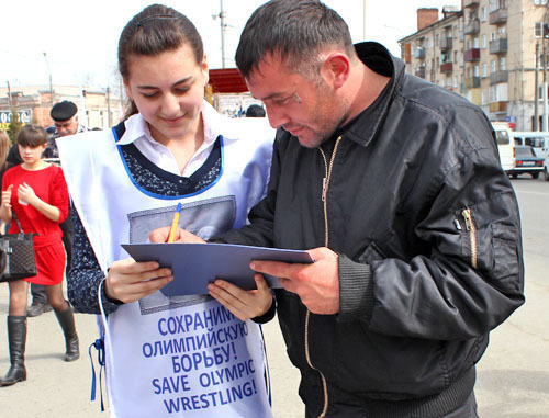 Флеш-моб за сохранение борьбы как олимпийского вида спорта прошел возле кинотеатра "Дружба". На снимке: волонтер собирает подписи. Владикавказ, 15 марта 2013 г. Фото Эммы Марзоевой для "Кавказского узла"